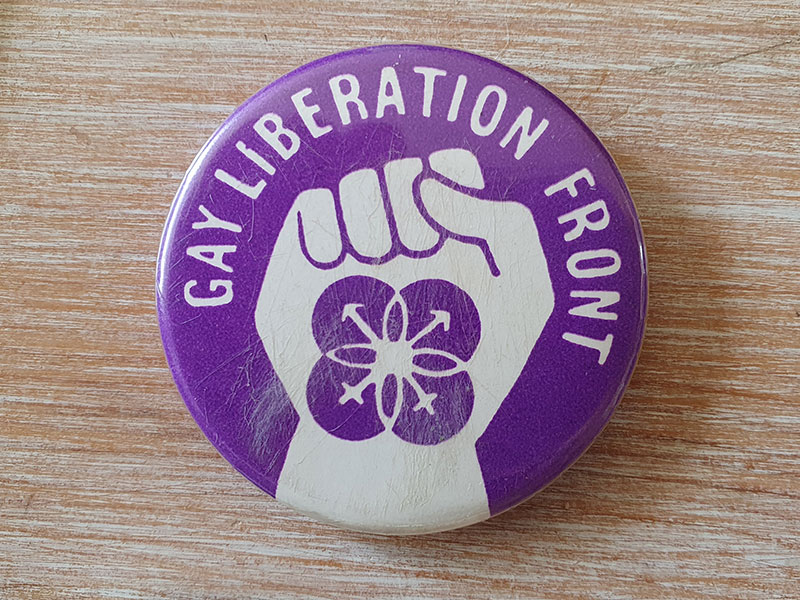 Purple badge with a fist and the words Gay Liberation Front