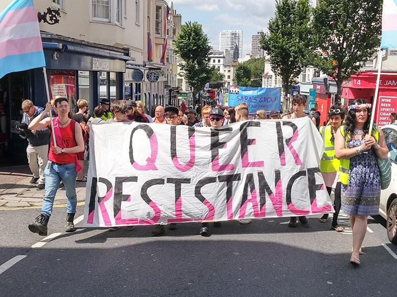 The front of a march with a banner that says Queer Resistance