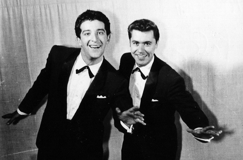 Two men in tuxedos smiling at the camera 