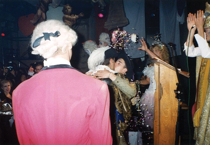 Two grooms kissing while confetti is thrown over them