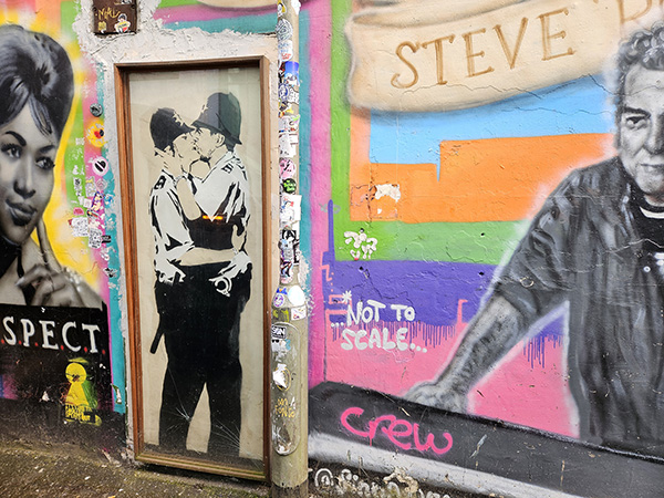 Black and white stencil of two male police officers kissing